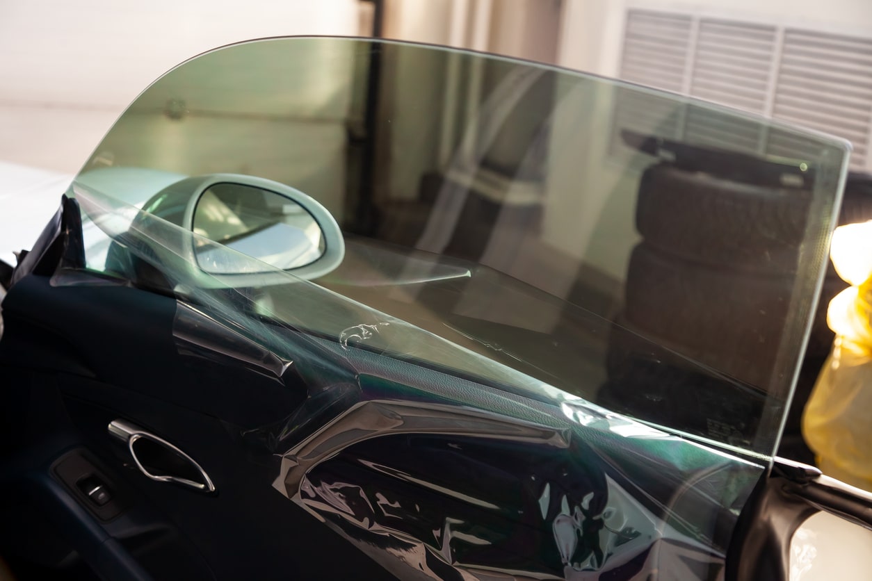 The process of tinting the glass of the car in the workshop for the installation of additional equipment with an unstuck protective film