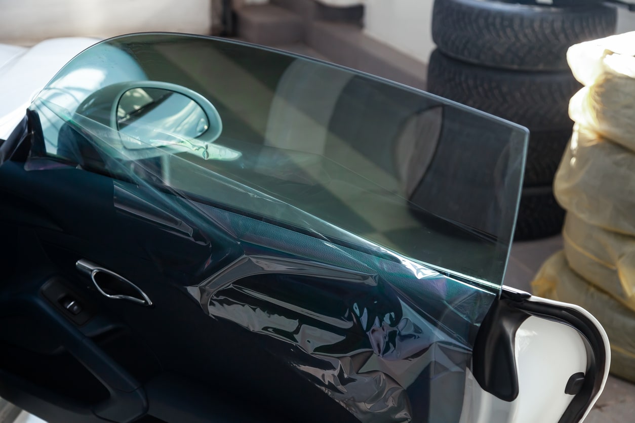 The process of tinting the glass of the car in the workshop for the installation of additional equipment with an unstuck protective film