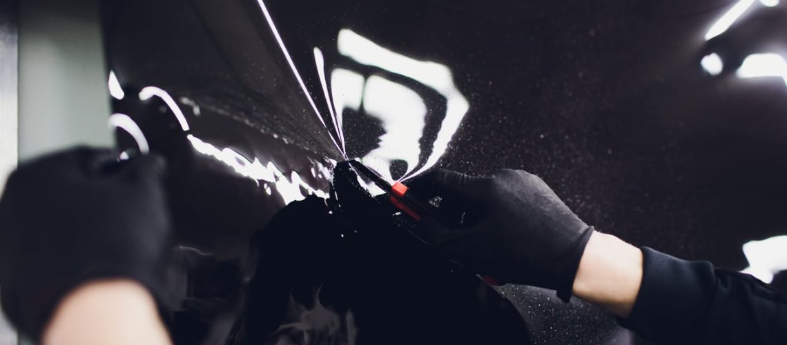 Applying tinting foil on a car window in a garage