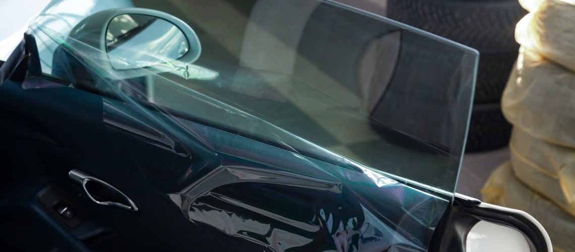 The process of tinting the glass of the car in the workshop for the installation of additional equipment with an unstuck protective film