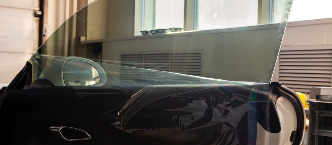 The process of tinting the glass of the car in the workshop for the installation of additional equipment with an unstuck protective film