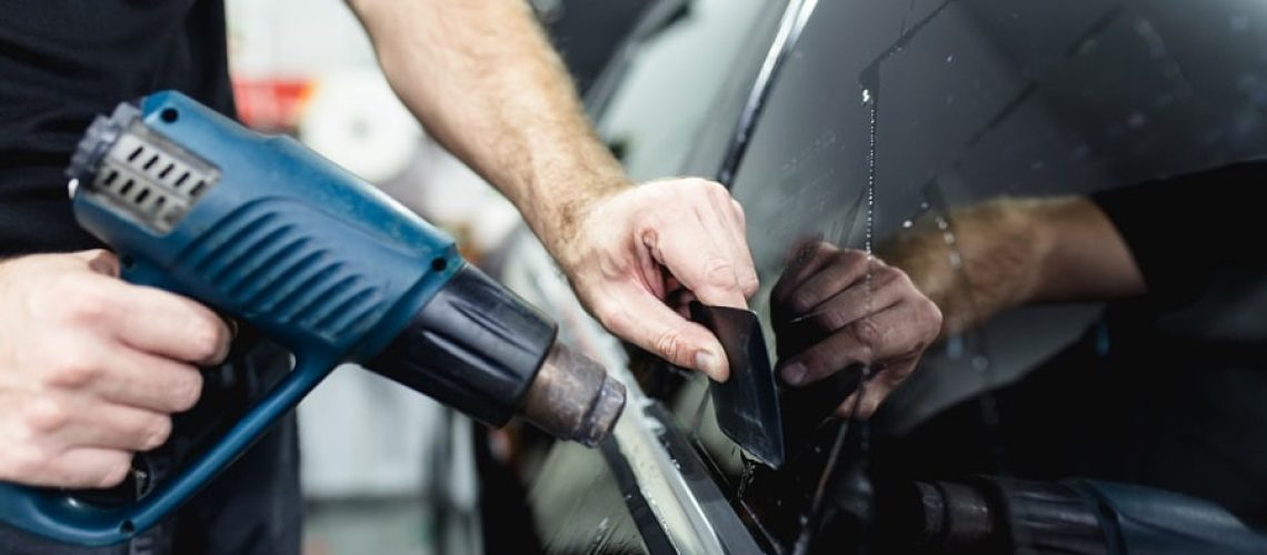 Car tinting - Worker applying tinting foil on car window.